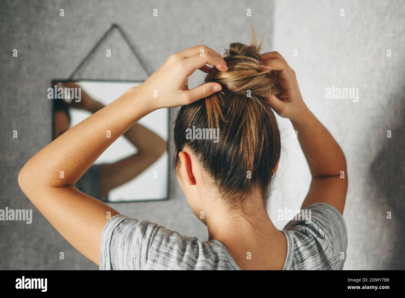 Mädchen macht Frisur oder Frisur vor einem Spiegel im Zimmer Stockfoto