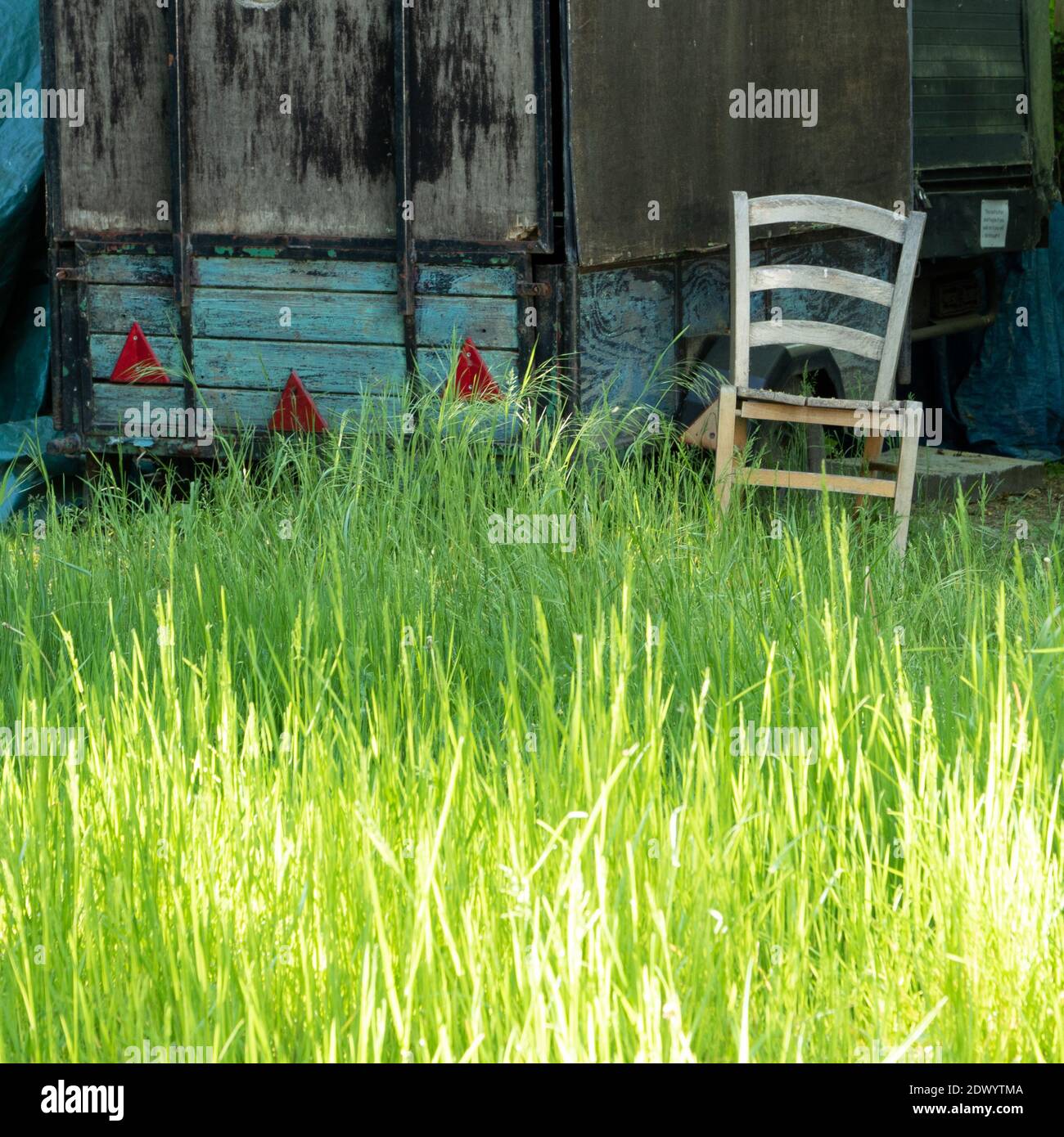 Abstrakt heruntergekommener Box Anhänger in Gras und Stuhl geparkt Stockfoto