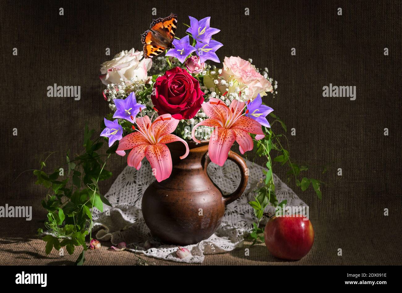 Stillleben mit einem Blumenstrauß in einem Krug und einem Apfel auf einem Hintergrund von Sackleinen. Selektiver Fokus Stockfoto