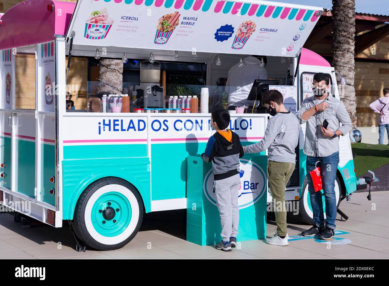 Valencia, Spanien. Dezember 2020. Ein Mann und zwei Kinder mit Gesichtsmasken kaufen im Bonaire Einkaufszentrum in einem Food Truck Eis. Kredit: Xisco Navarro/SOPA Images/ZUMA Wire/Alamy Live Nachrichten Stockfoto