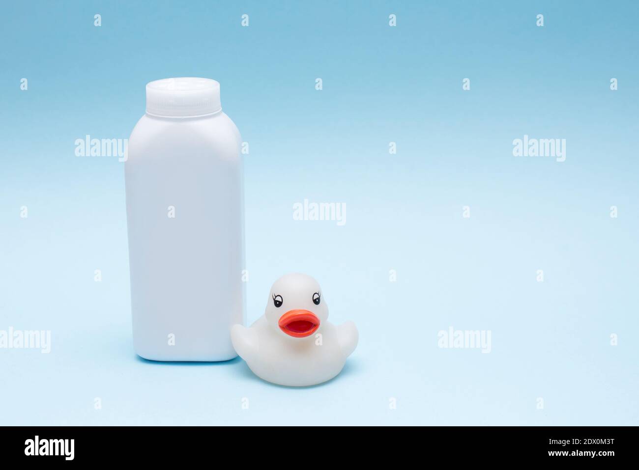 Baby Puderflasche und kleine Spielzeug Ente auf blauem Hintergrund. Stockfoto