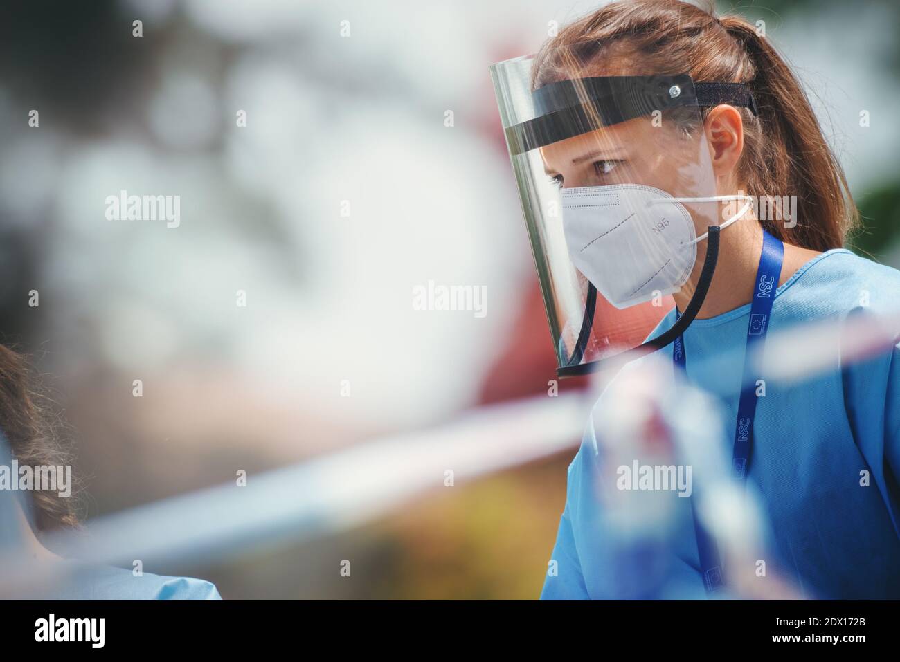 Medizinische Mitarbeiterin mit einem Atemschutzgerät und einem Gesichtsschutz aus Kunststoff, der auf der Straße steht. Stockfoto