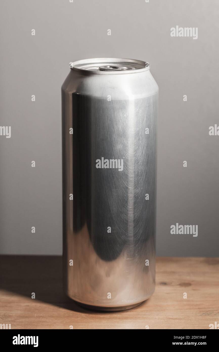 Geschlossene glänzende Aluminium-Dose steht auf einem Holztisch, Standard-Softdrink-Verpackung, vertikales Foto Stockfoto