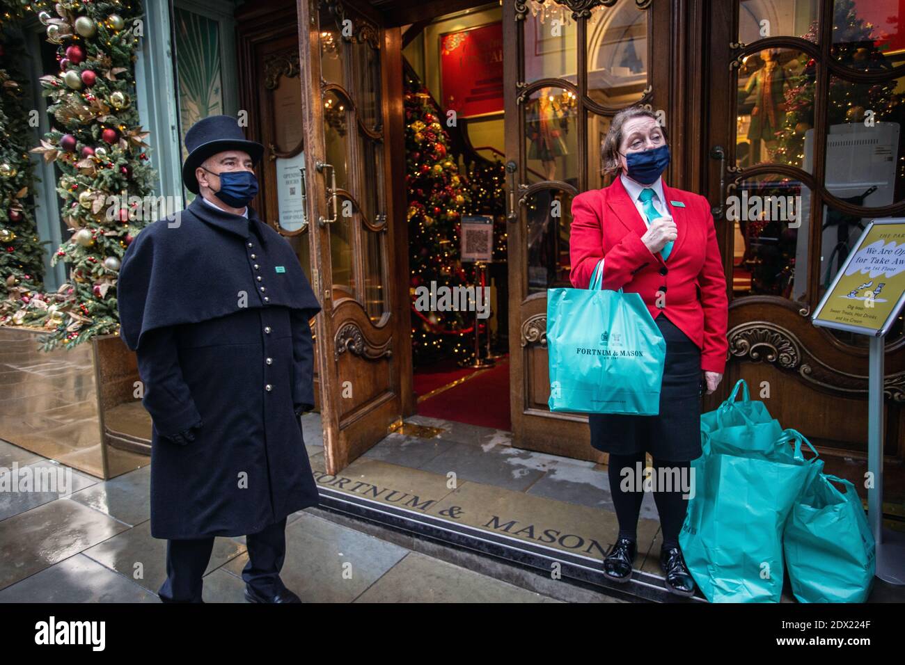 England/London/Piccadilly/Türsteher mit Gesichtsmaske wegen der COVID-19 Pandemie, am 23. Dezember 2020 bei Fortnum & Mason in London. Stockfoto