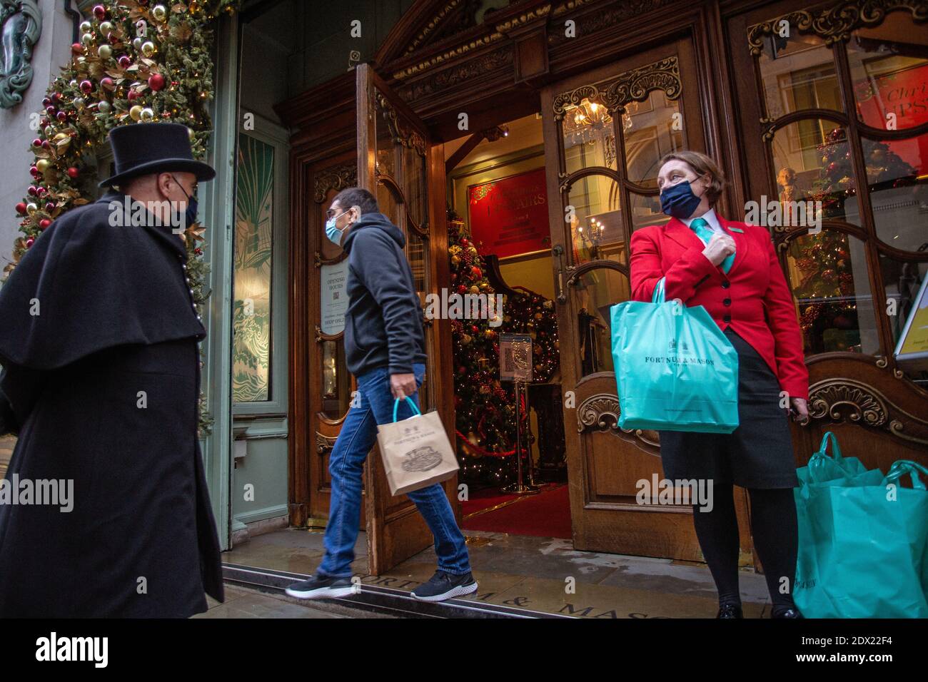 England/London/Piccadilly/Türsteher mit Gesichtsmaske wegen der COVID-19 Pandemie, am 23. Dezember 2020 bei Fortnum & Mason in London. Stockfoto