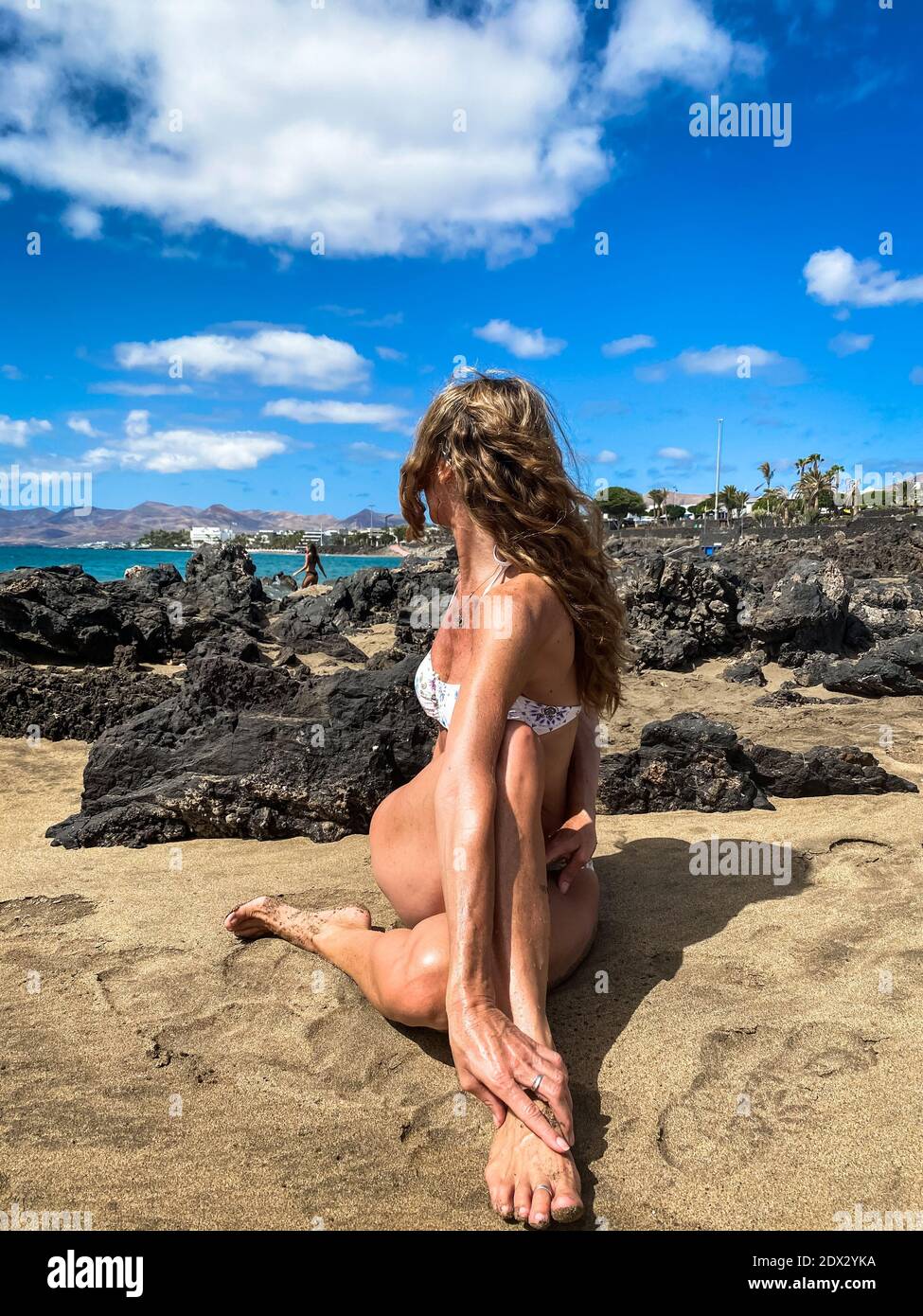 Flexible Frau im Bikini, der halb herr der Fische durchführt, posieren auf dem felsigen Strand. Yoga Fortgeschrittene Praktiker in ardha matsyendrasana im Freien Stockfoto