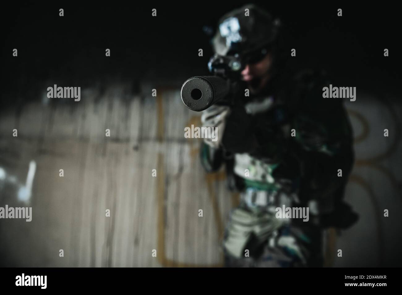Soldat in voller US MARSOC bewaffnet mit Sturmgewehr durch das verlassene Gebäude laufen. Militärischer Zusammenstoß. Stockfoto