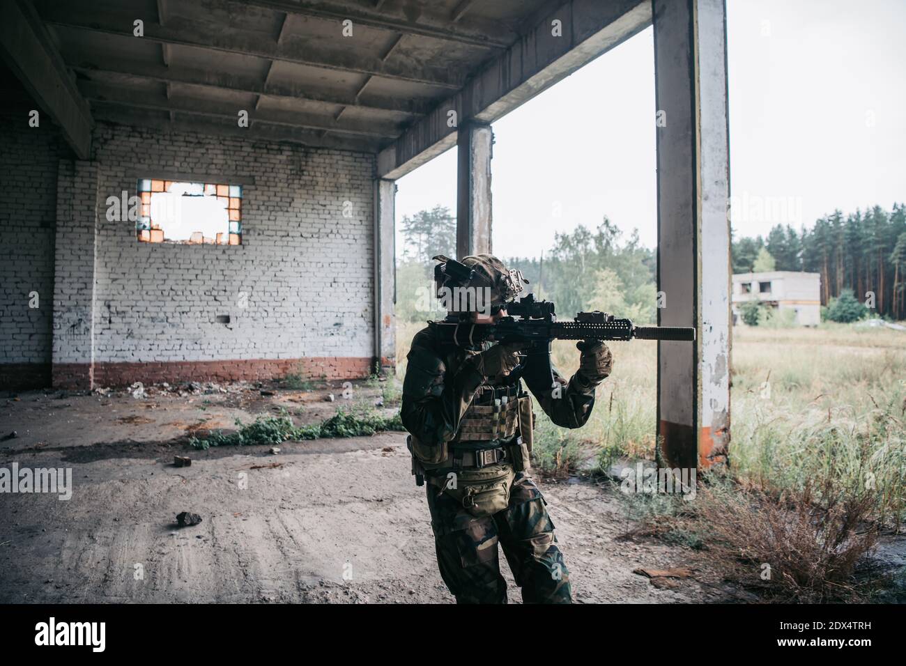 Soldat in voller US MARSOC bewaffnet mit Sturmgewehr durch das verlassene Gebäude laufen. Militärischer Zusammenstoß. Stockfoto