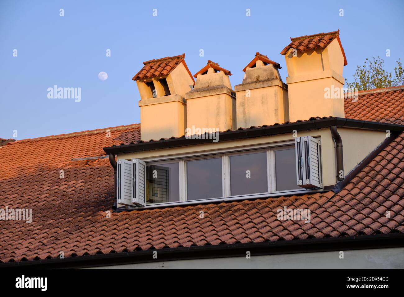 Gefliestes Dach mit vier Fensterscheiben und Kaminen Am blauen Himmel Stockfoto