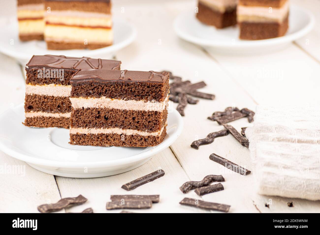 Schokoladenkuchen mit drei Schokoladenteig und zwei Cremetöden. Ideale Hochzeit und Feier Dessert. Köstliche Pie auf weißem Holztisch serviert. Stockfoto