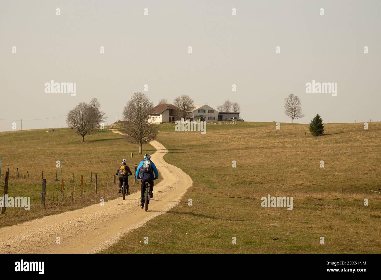 Zwei Mountainbiker auf einer Schotterstraße vor Ein Bauernhof im Schweizer Jura Stockfoto