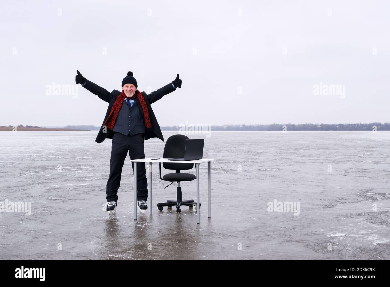 Geschäftsmann im Anzug steht mit ausgestreckten Händen an einem Tisch In der Mitte See Stockfoto