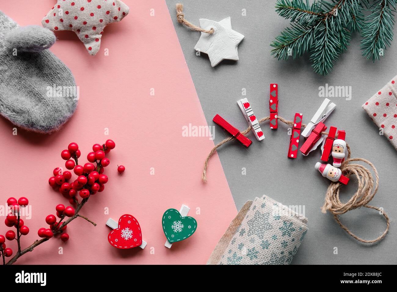 Nachhaltige Naturgeschenke für Zero Waste Weihnachten.Handschuhe, weiches Spielzeug, Holzpflöcke und natürliche Beeren. Layered pink grau Papier flach legen.. Stockfoto