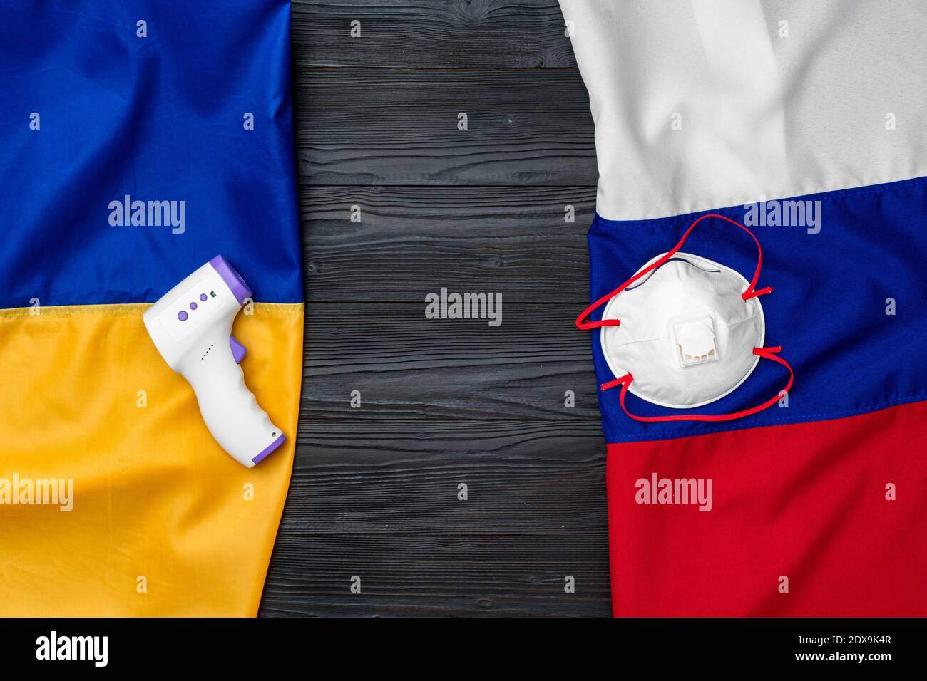 Flaggen von Russland und der Ukraine auf hölzernen Hintergrund mit medizinischen Masken Stockfoto