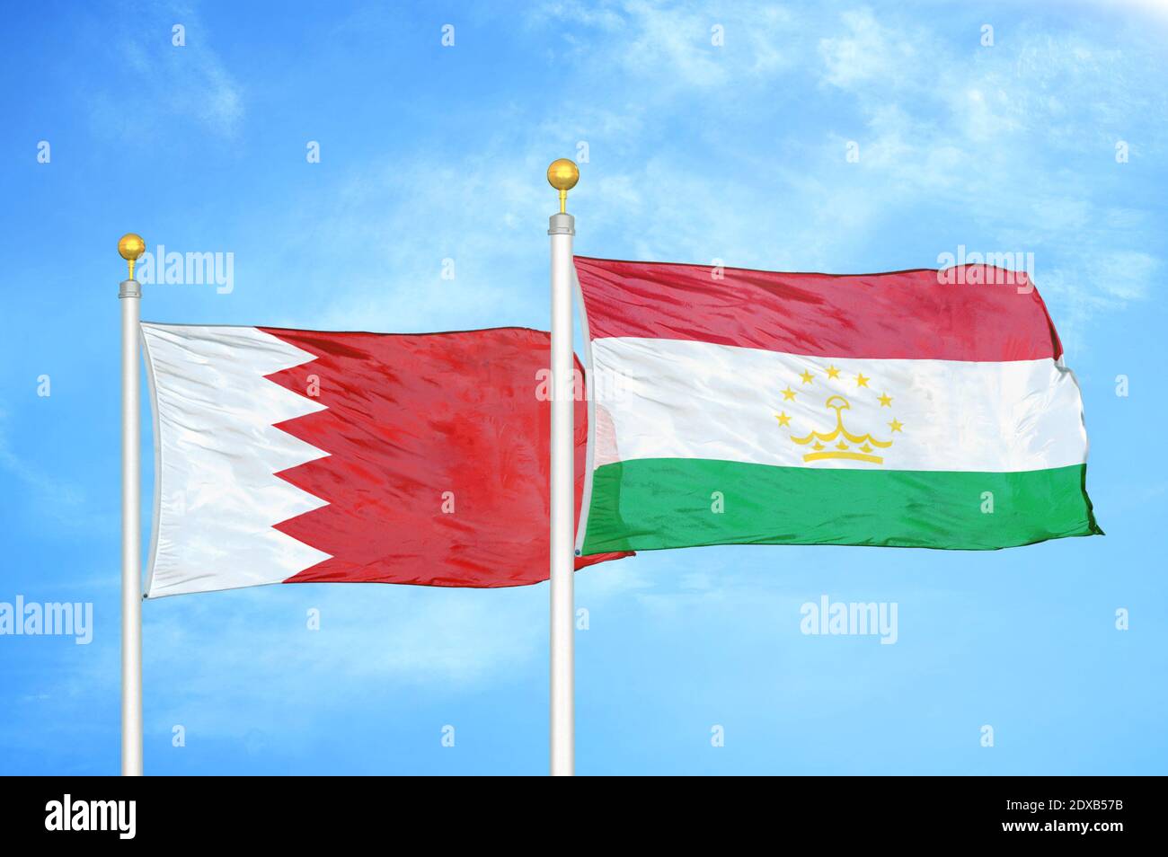 Bahrain und Tadschikistan zwei Flaggen auf Fahnenmasten und blauer Himmel Stockfoto