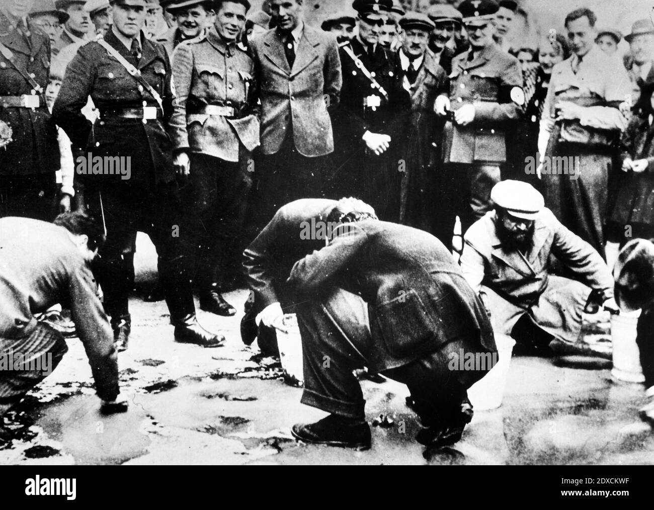 Österreichische Nazis und Anwohner sehen zu, wie Juden gezwungen sind, auf ihre Hände und Knie zu gehen und den Bürgersteig zu schrubben. Datum: März 1938 - April 1938 Ort: Wien, Österreich Stockfoto