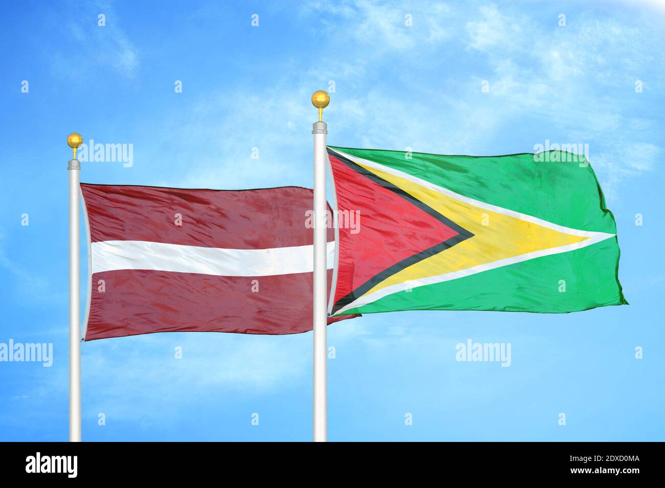 Lettland und Guyana zwei Flaggen auf Fahnenmasten und blauer Himmel Stockfoto