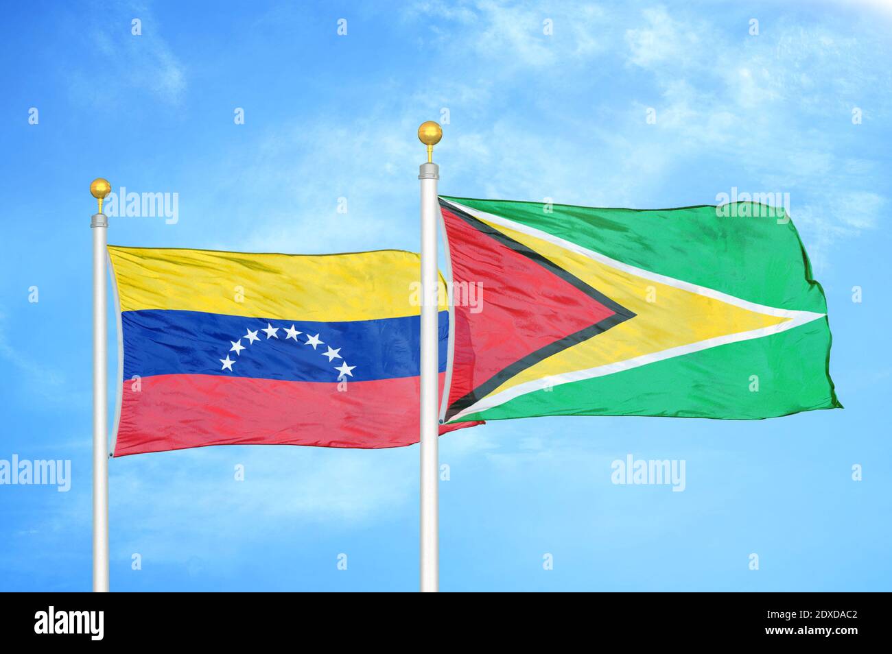 Venezuela und Guyana zwei Flaggen auf Fahnenmasten und blauer Himmel Stockfoto