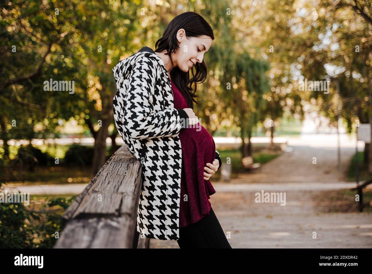 Schwangere Frau berührt Magen, während im Park stehen Stockfoto
