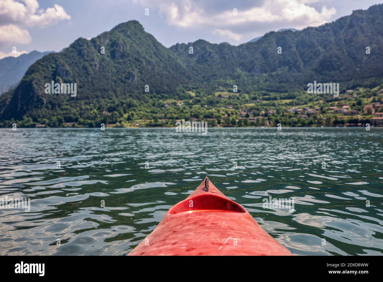 Kajakboot schwimmt auf dem Idrosee vor den Bergen Stockfoto