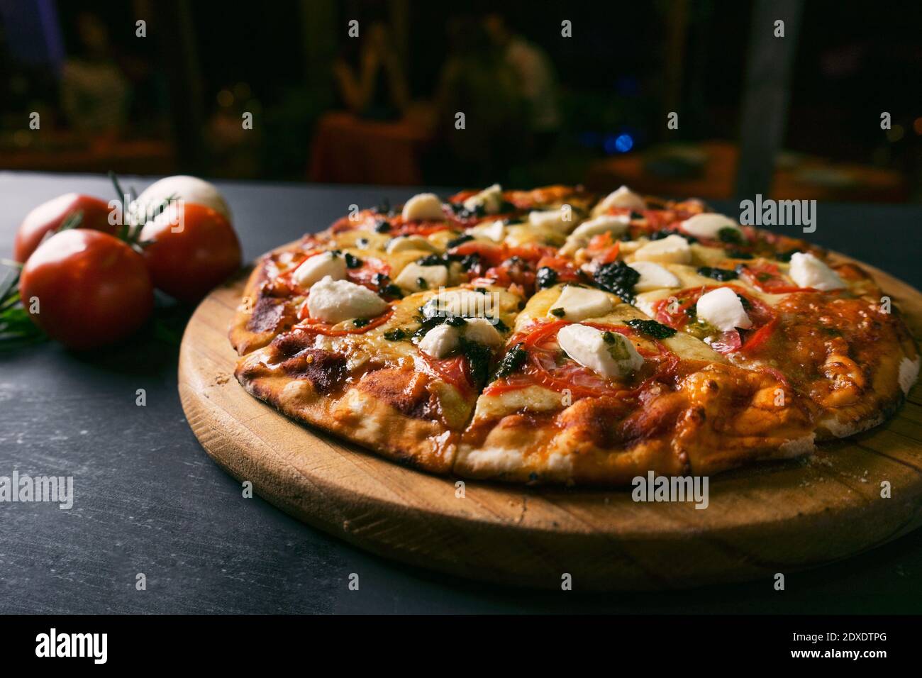 Draufsicht traditionelle italienische Pizza mit grünen Basilikum Pesto-Sauce auf einem schwarzen rustikalen Holzhintergrund. Restaurant verwischen Hintergrund Stockfoto