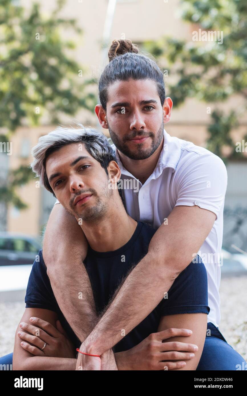 Selbstbewusster Mann mit männlichem Partner, der in der Stadt sitzt Stockfoto