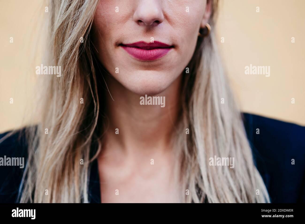 Nahaufnahme einer Frau mit rosa Lippenstift an der gelben Wand Stockfoto