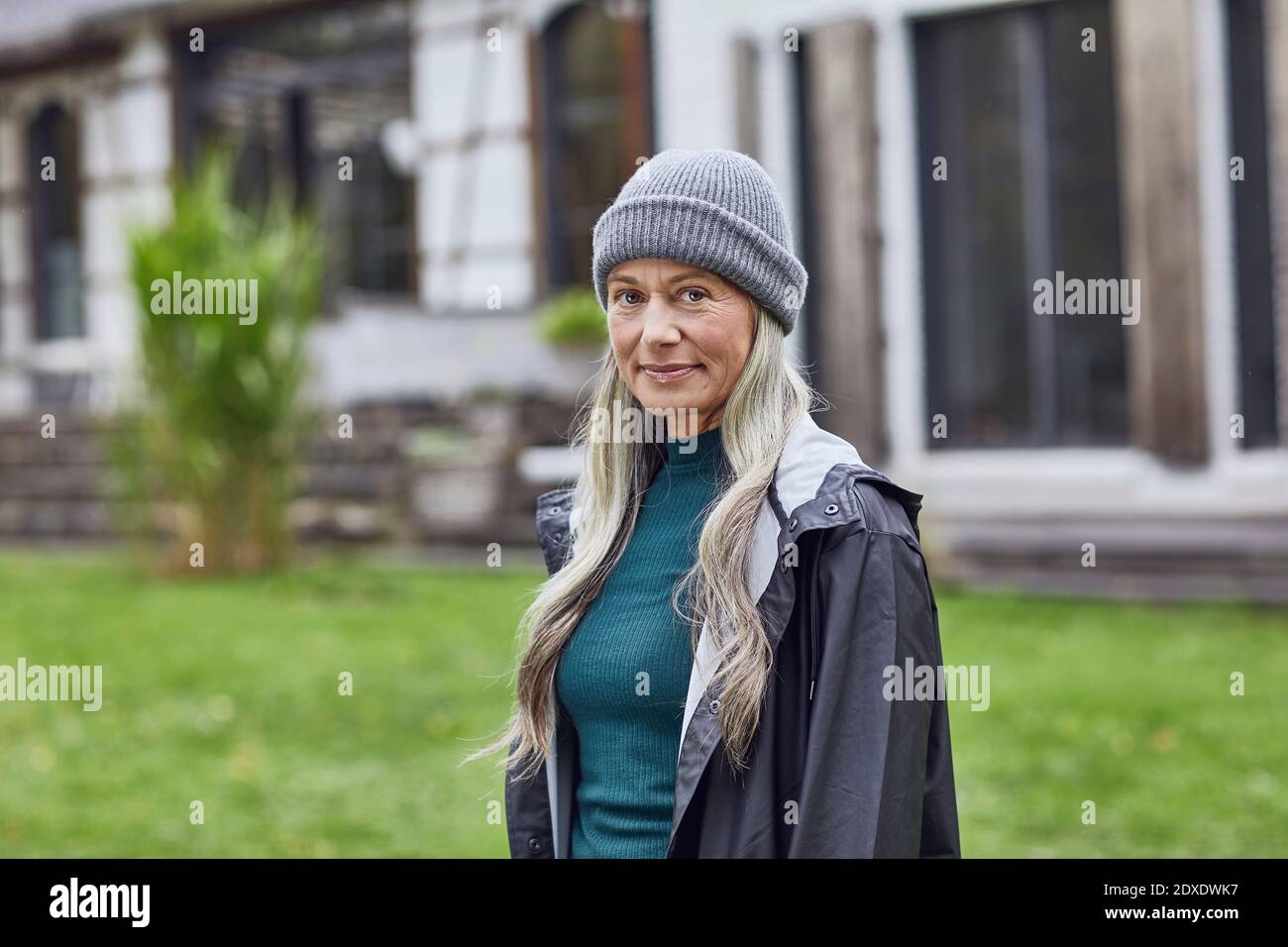 Selbstbewusste reife Frau trägt Strickmütze im Hinterhof Stockfoto