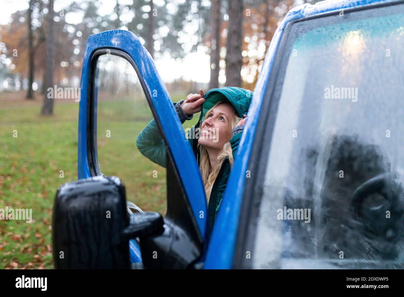 Lächelnde Frau, die am regnerischen Tag im Cannock Chase Haare bedeckt Stockfoto