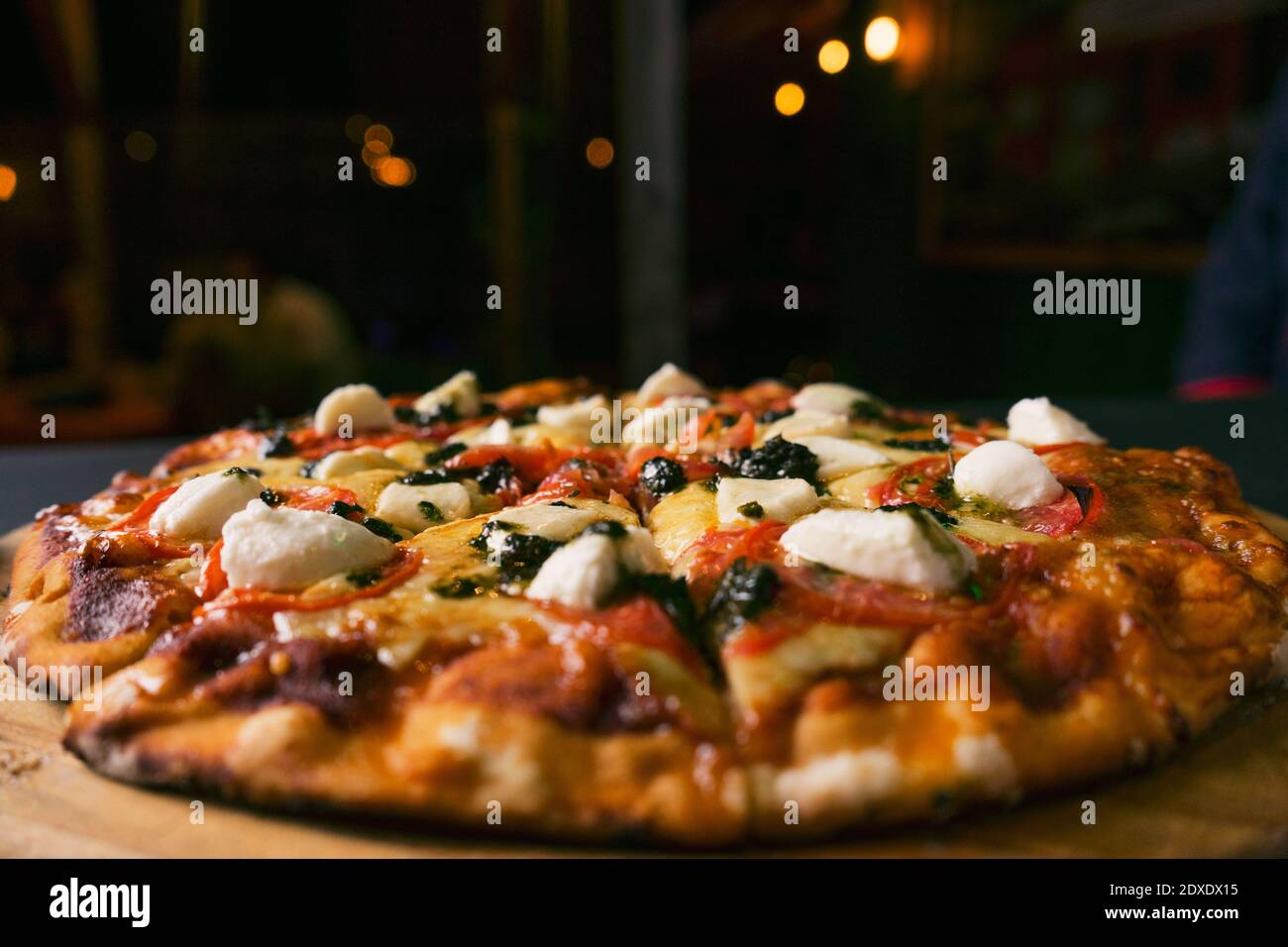 Draufsicht traditionelle italienische Pizza mit grüner Basilikum-Pesto-Sauce Auf einem schwarzen rustikalen Holzhintergrund.Restaurant verwischen Hintergrund Stockfoto