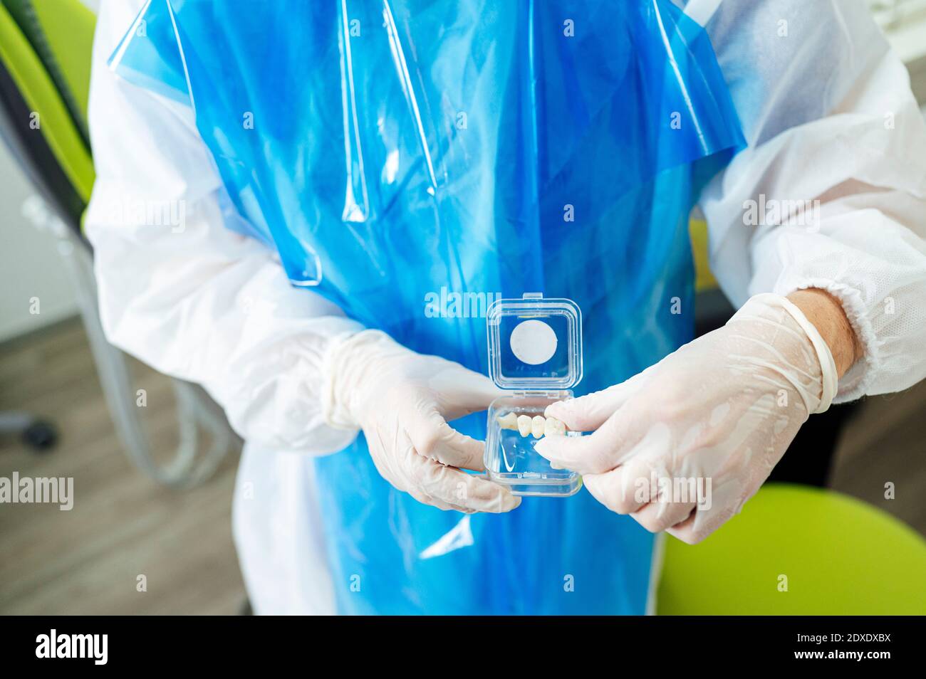 Zahnärztin trägt schützende Arbeitskleidung hält Zähne Box während des Stehens In der Klinik Stockfoto