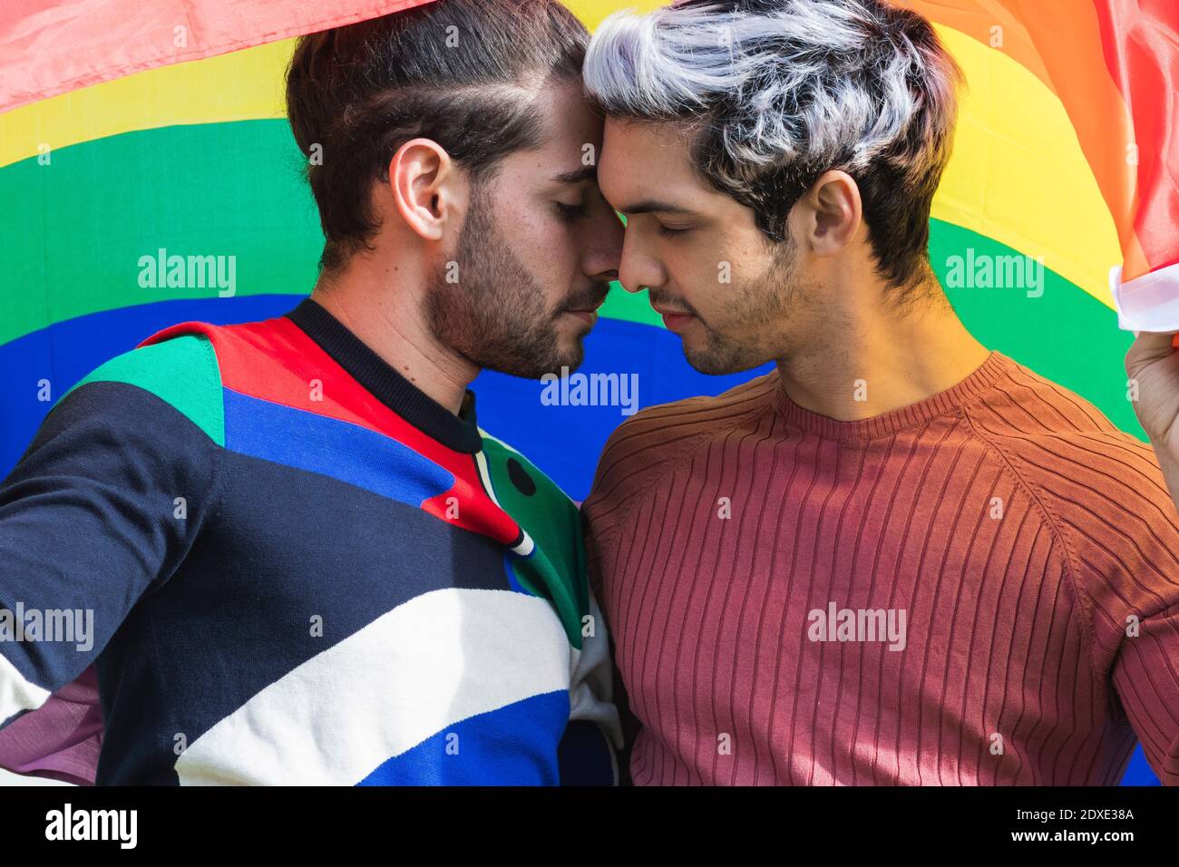 Liebevoller Mann flirtet mit männlichem Partner gegen Regenbogen Schal Stockfoto