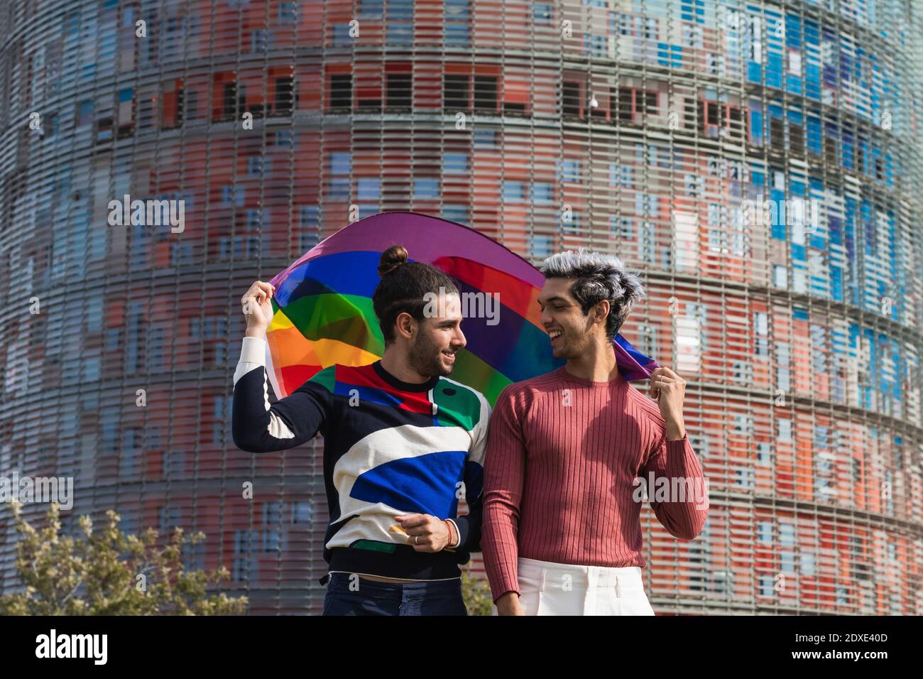 Lächelnd liebevoller Mann mit Regenbogen Schal Blick auf Homosexuell Partner In der Stadt Stockfoto
