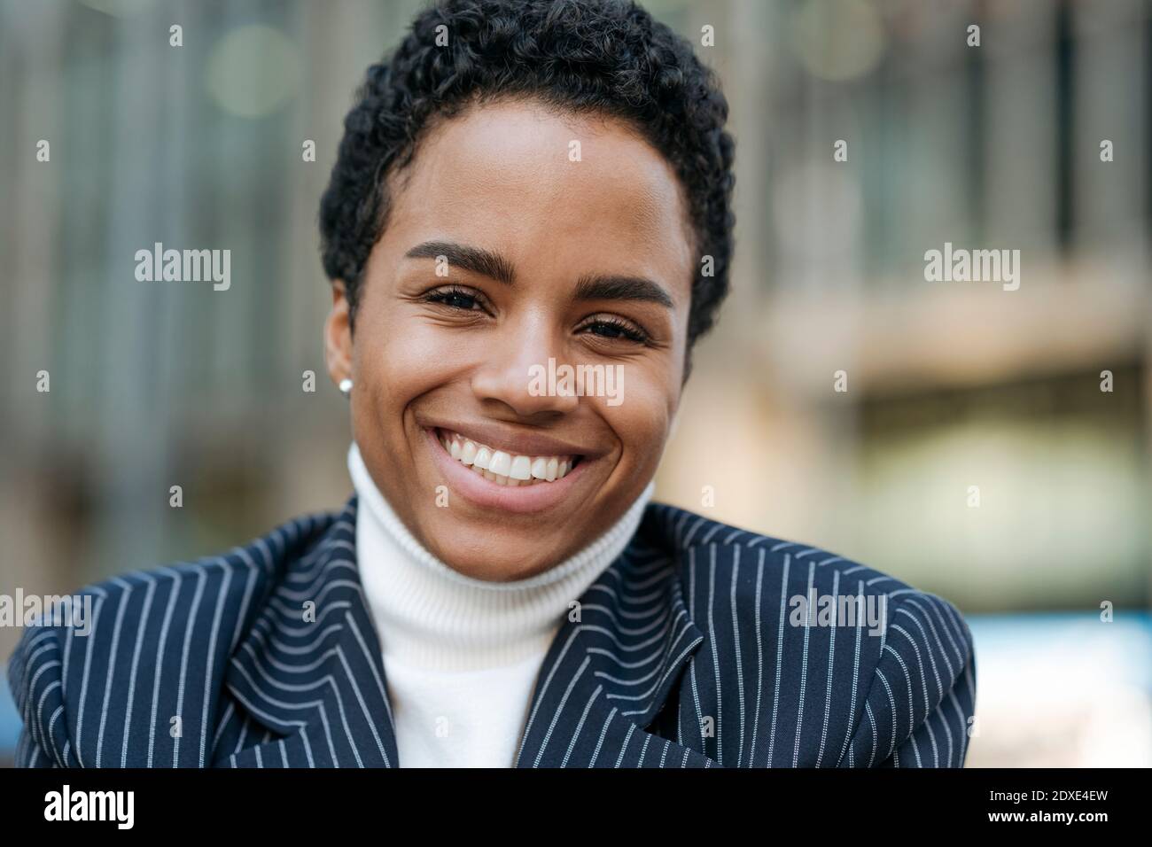 Lächelnde junge Geschäftsfrau mit kurzen Haaren trägt Blazer Stockfoto