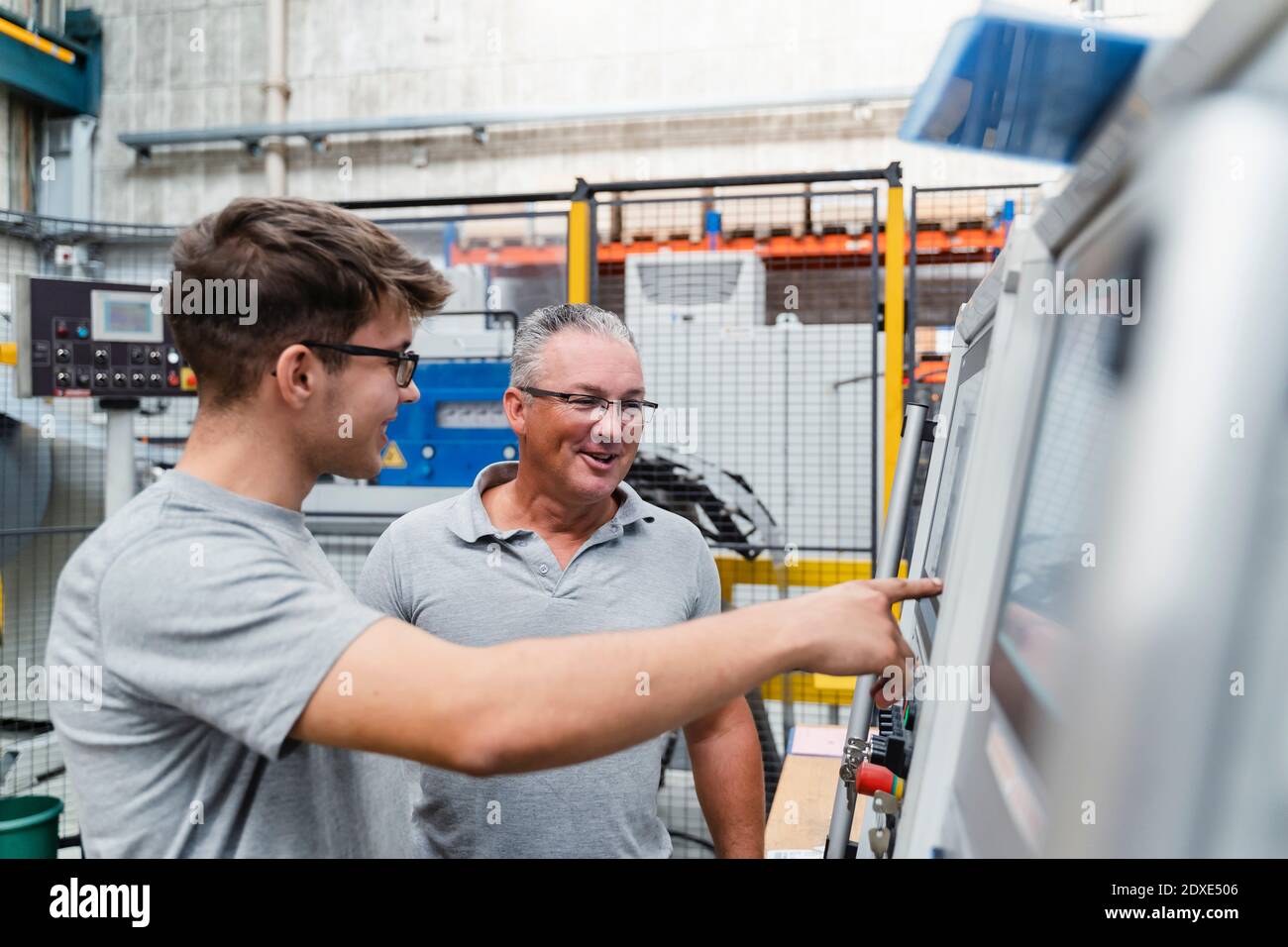 Lächelnd männliche manuelle Arbeiter Untersuchung Maschine in der Industrie Stockfoto