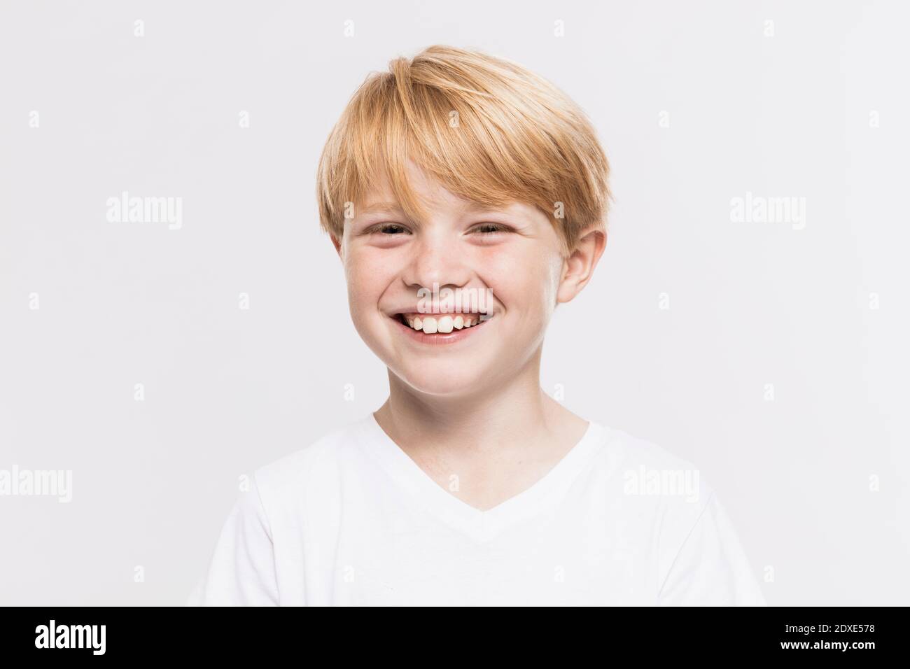 Fröhlicher netter Junge mit blonden Haaren vor weißem Hintergrund Stockfoto
