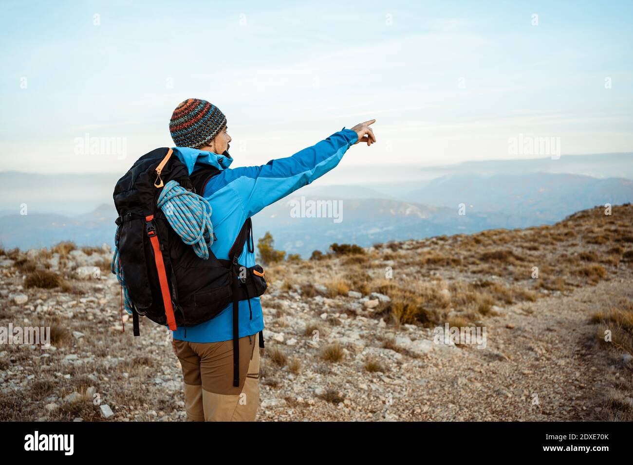 Männlicher Wanderer zeigt beim Blick auf den Blick vom Berg während Urlaub Stockfoto