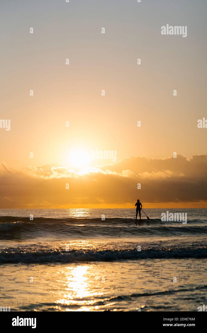 Silhouette Frau Surfen mit Paddleboard auf Mittelmeer im Morgengrauen Stockfoto