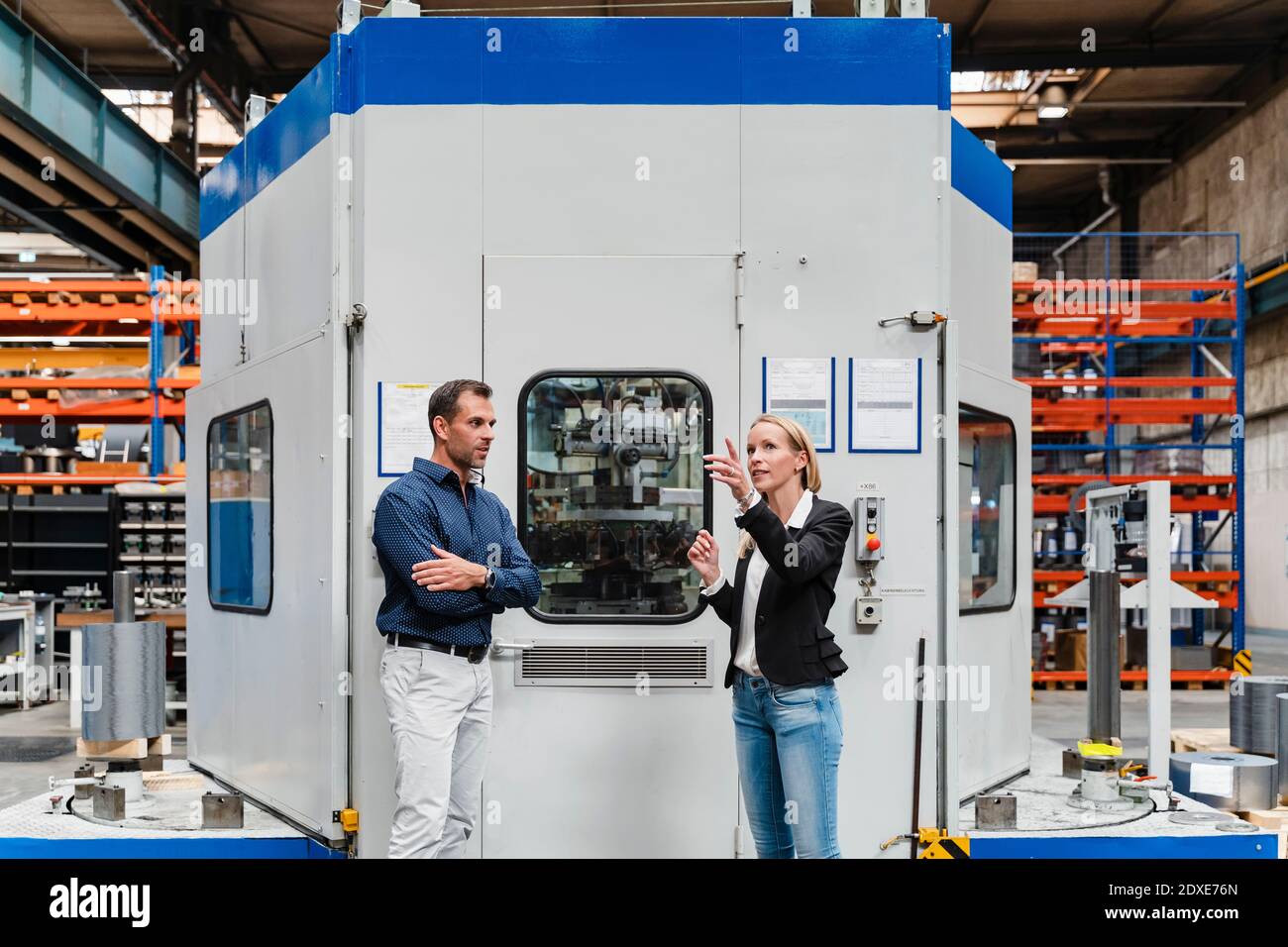 Unternehmerin erklärt männlichen Kollegen, während sie gegen die Kontrollkammer steht In der Industrie Stockfoto
