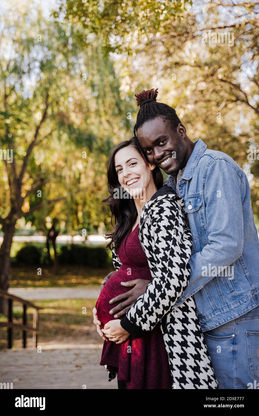 Glückliche schwangere Frau, die mit Mann im Park steht Stockfoto