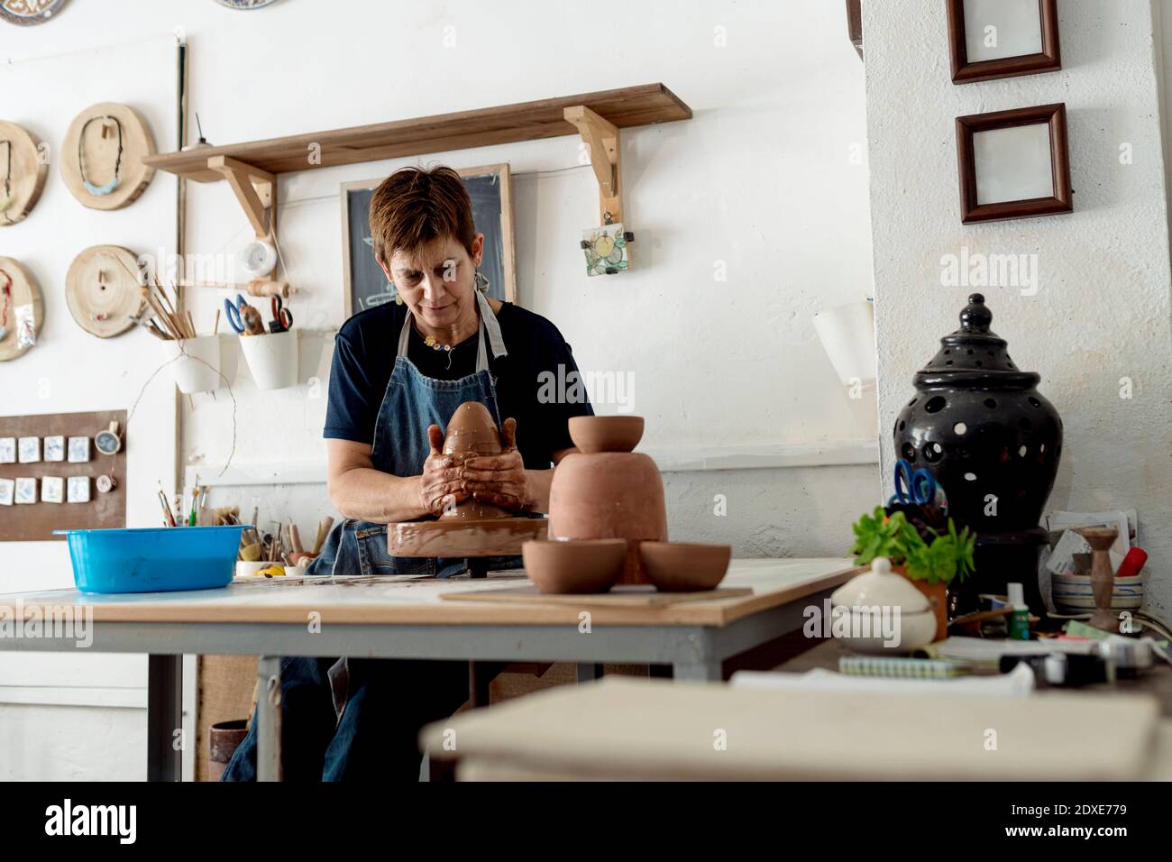 Reife Künstlerin macht Keramik aus braunem Ton in Keramik Speichern Stockfoto