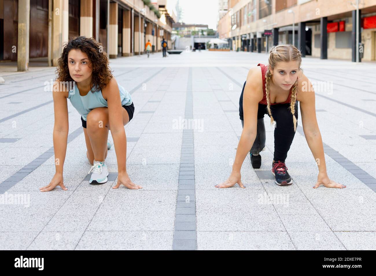 Sportlerinnen hocken für Sportrennen auf Fußwegen in der Stadt Stockfoto