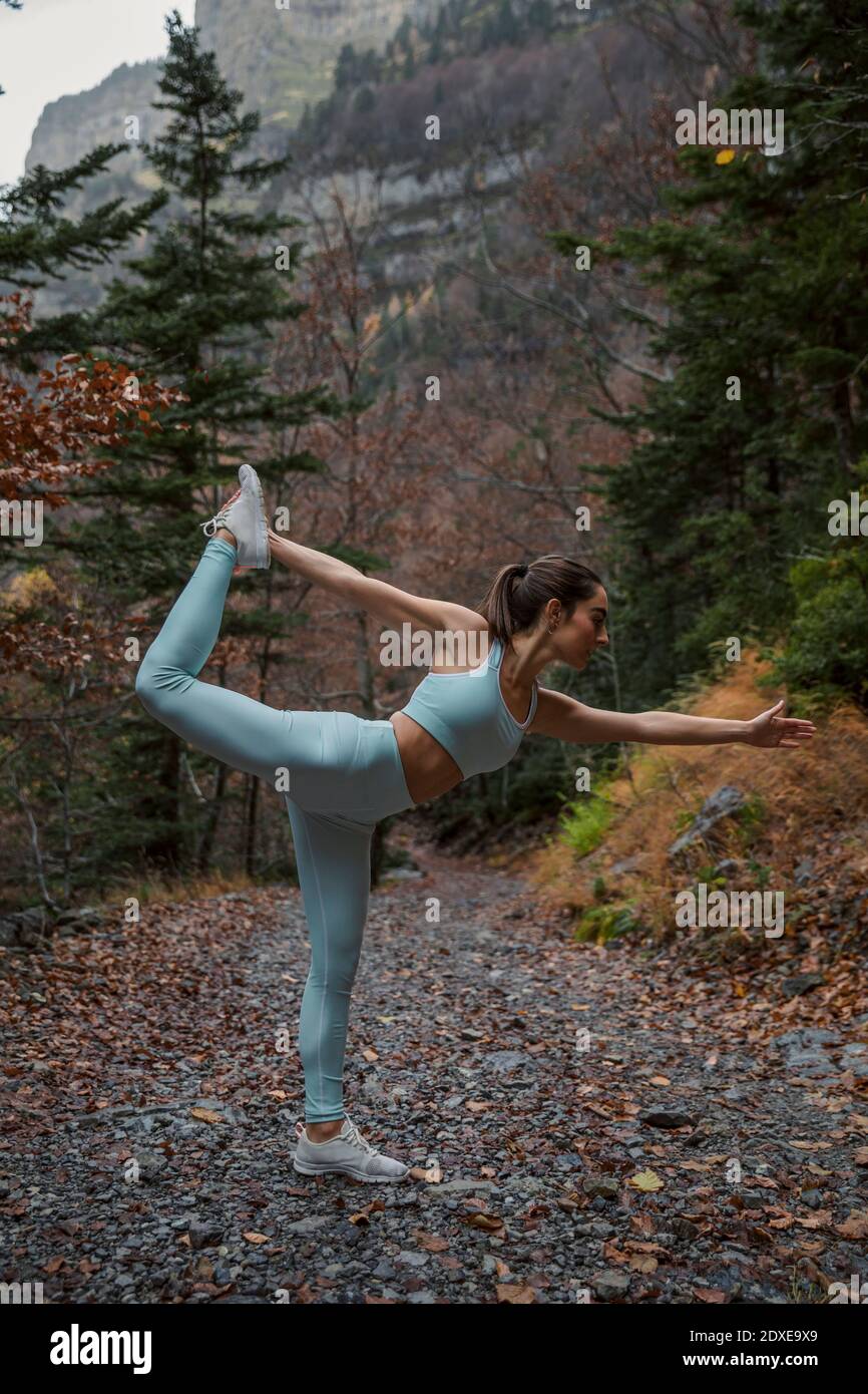 Weibliche Athletin, die rhythmische Gymnastik macht, während sie im Wald steht Stockfoto