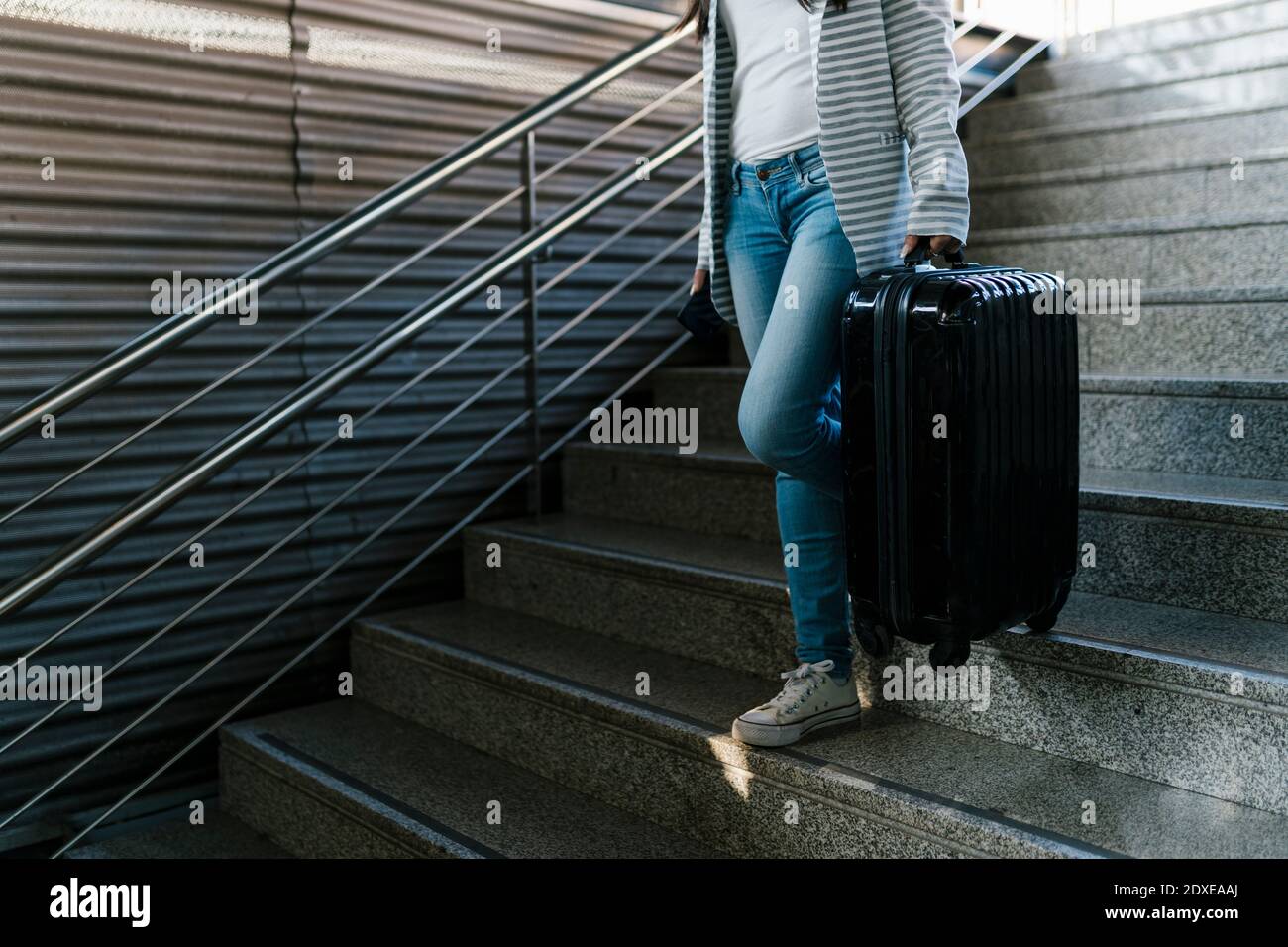 Weibliche Fahrgastin mit Gepäck, die sich auf den Stufen der U-Bahn nach unten bewegt Station Stockfoto