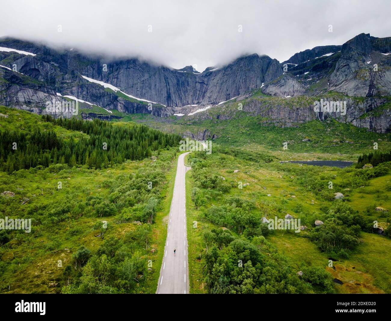 Frau auf dem Weg gegen den Berg am Nusfjord, Lofoten, Norwegen Stockfoto