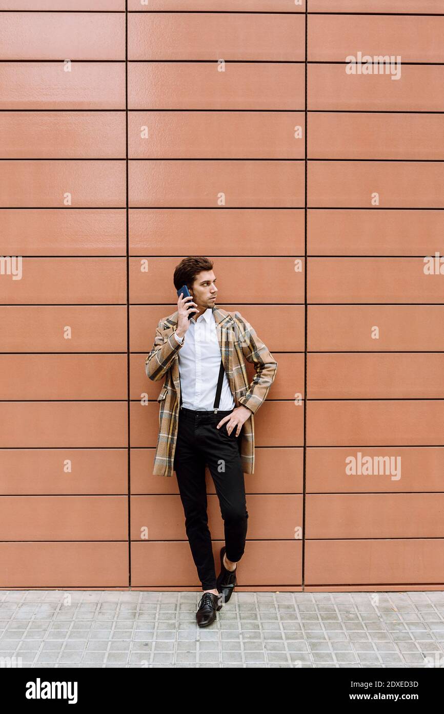 Stilvoller junger Mann mit Smartphone, der im Gebäude steht Stockfoto
