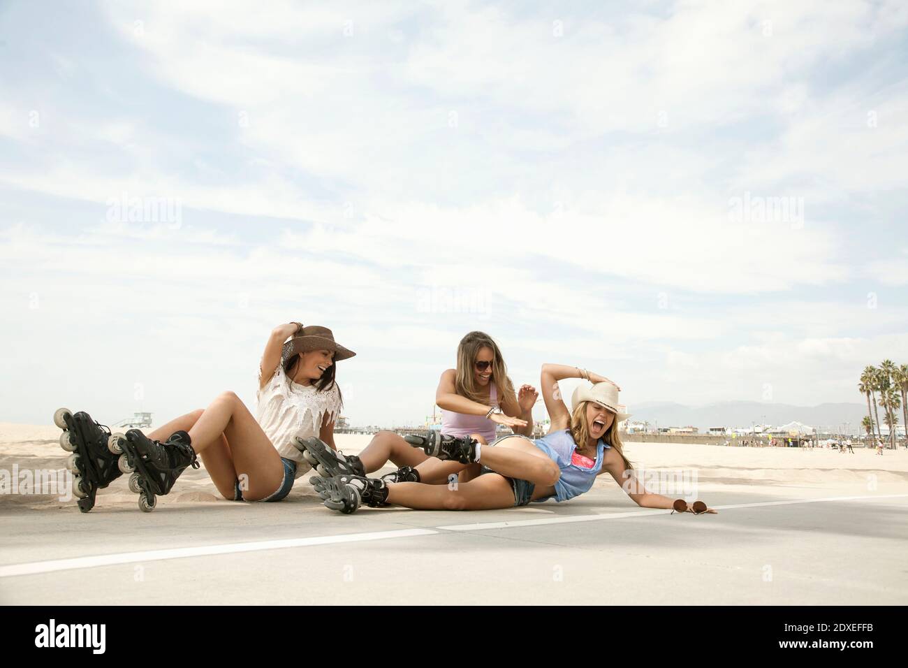 Fröhliche Frauen lachen, während sie auf der Straße am Strand fallen Wochenende Stockfoto