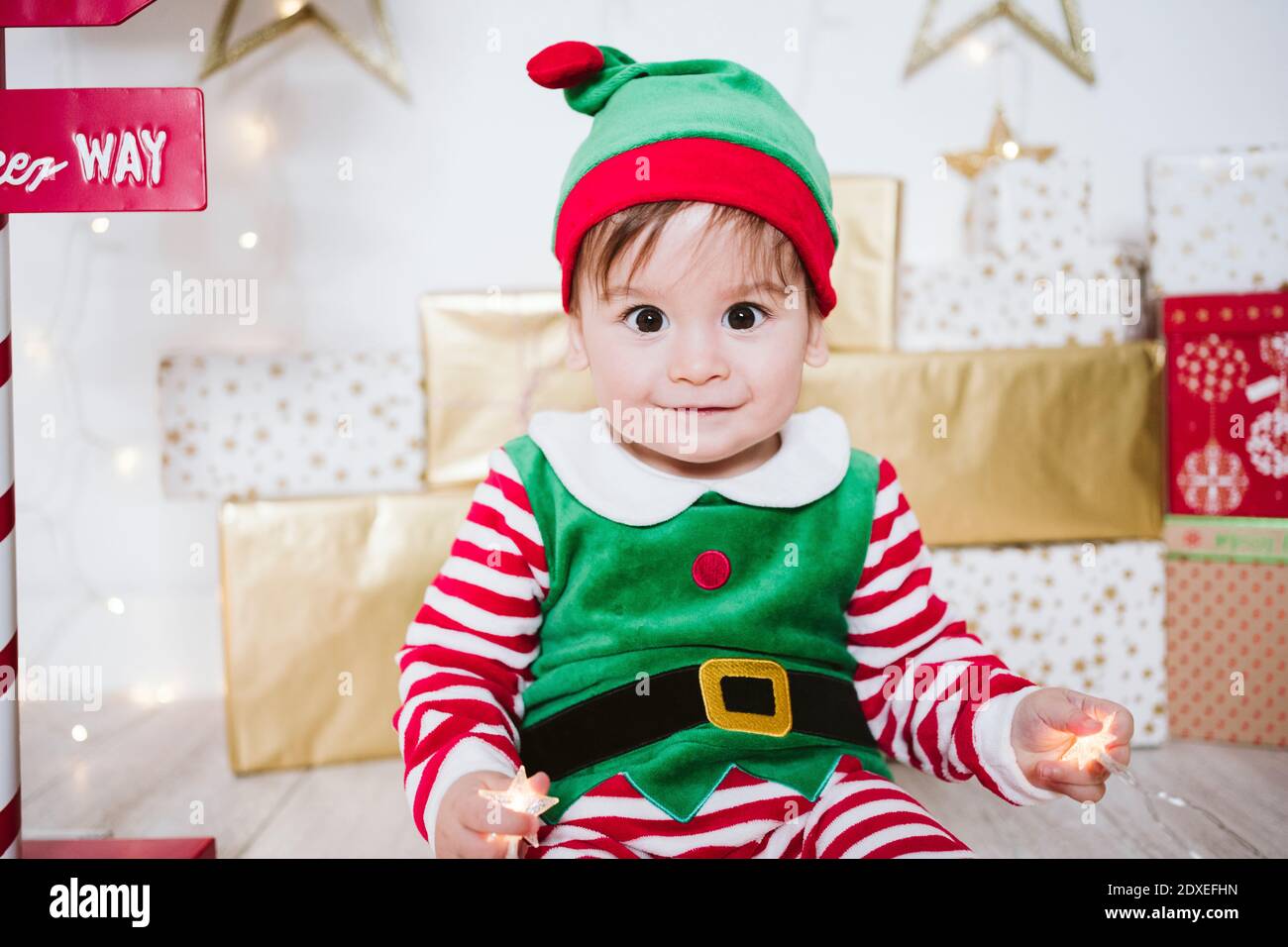Niedlichen Baby Junge in elf Kostüm spielen, während sitzen an Zuhause während Weihnachten Stockfoto