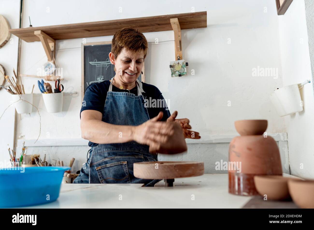 Lächelnde weibliche Töpfer arbeiten mit braunem Ton in Keramik-Shop Stockfoto