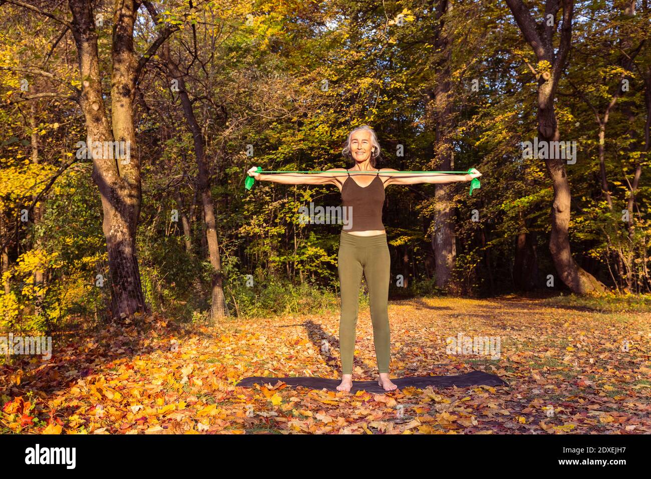 Reife Frau Training mit Widerstand Band im Park im Herbst Stockfoto